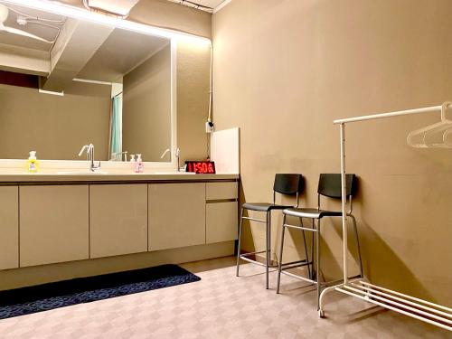 釜山韩国宿旅舍的浴室设有水槽、镜子和2把凳子