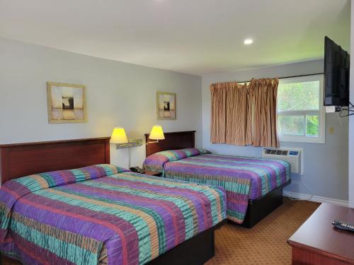 科堡Knights Inn Cobourg的一间酒店客房,设有两张床和电视