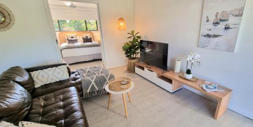努萨维尔Noosa River Retreat Apartments - Perfect for Couples & Business Travel的客厅配有真皮沙发和电视