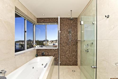 尼尔森湾Penthouse Palace - Luxurious Harbourview Location的带浴缸和玻璃淋浴间的浴室。