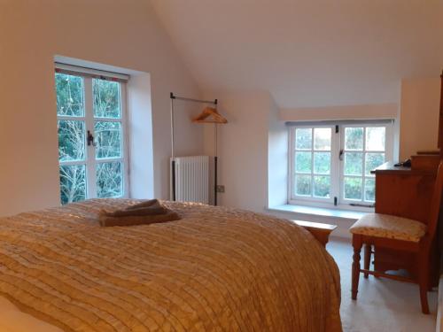 BrockleyCharacterful Cottage adjacent to an Orchard的一间卧室设有一张大床和两个窗户。