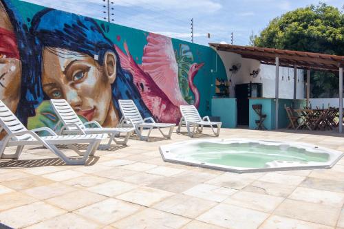 福塔莱萨Salve Maloca Hostel的建筑前方的壁画,内有椅子和热水浴池