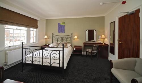 莱奇沃思百老汇酒店的一间卧室配有一张床、一张桌子和一把椅子