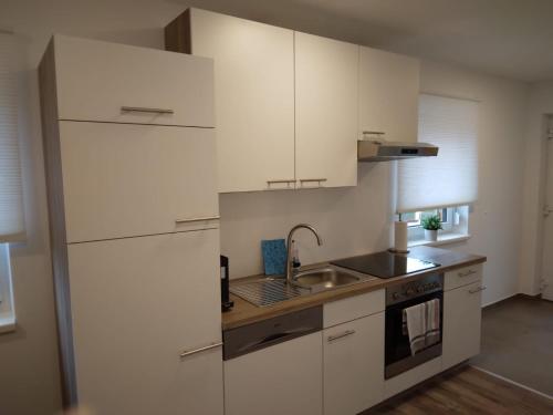 洛伊查赫Appartement Fam.Kremser的厨房配有白色橱柜和水槽