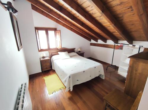 Pesaguero-La ParteLa Huertona的卧室设有白色的床和木制天花板。