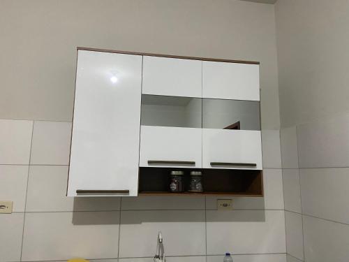 巴纳内拉斯Casa agradável no centro的厨房配有白色橱柜和水槽上方的镜子