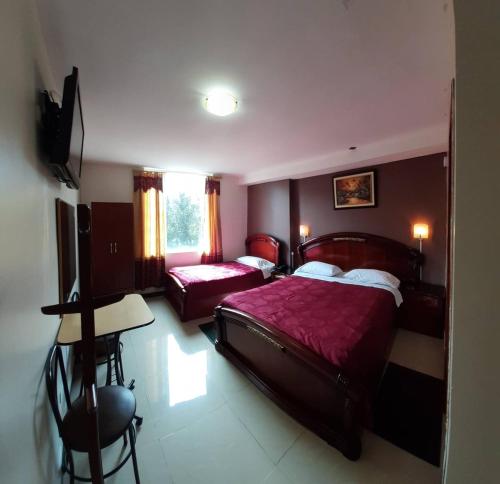 Hacienda CarrionaHotel Del River的一间卧室配有两张床、一张桌子和一台电视。