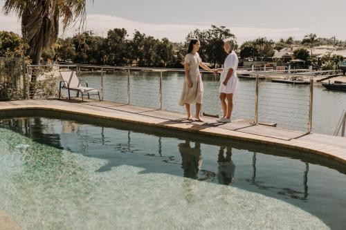 穆卢拉巴盐水别墅 - 乐宠住宿的两个女人站在游泳池旁边的码头上