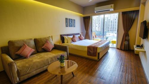 苏拉特Weekend Address managed by Global Hospitality的酒店客房设有沙发、床和桌子。