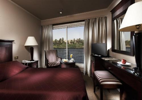 卢克索Jaz Crown Jubilee Nile Cruise - Every Thursday from Luxor for 07 & 04 Nights - Every MondayFrom Aswan for 03 Nights的配有一张床、一张书桌和一扇窗户的酒店客房