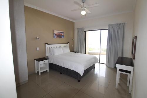 乌旺戈海滩Saints View Resort Unit 23的一间卧室配有一张床、一张书桌和一个窗户。