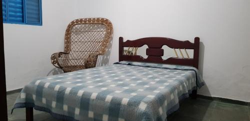 苏扎努Bela Chácara的一张带 ⁇ 子毯子的床,坐在椅子旁边