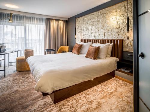 海滨诺德韦克亚历山大酒店的酒店客房设有一张大床和一张书桌。