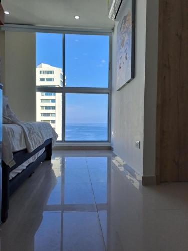 圣玛尔塔Apartamento frente al mar Rodadero Santa Marta的客房设有床和大窗户。
