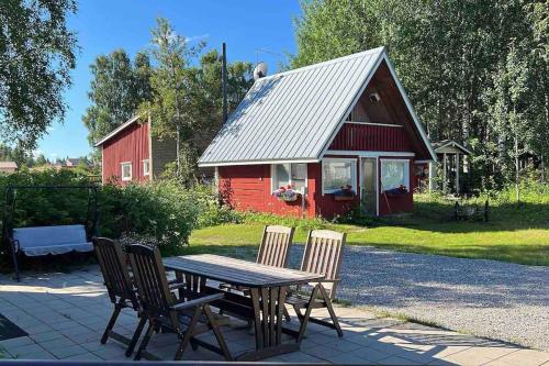 基蒂莱Adorable 1-bedroom cottage/guesthouse in Kittilä的红谷仓前的一张木桌和椅子