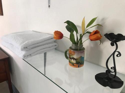 莱昂El Callejon Guest House的花瓶上的玻璃桌,上面有橙色花