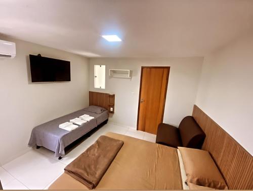 泰谢拉迪弗雷塔斯Pousada Avenida的一间卧室配有一张床、一张沙发和一台电视。