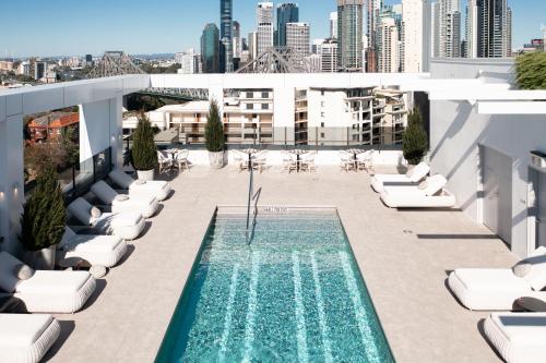 布里斯班Hotel X Brisbane Fortitude Vly, Vignette Collection - an IHG Hotel的一座带躺椅的建筑屋顶上的游泳池