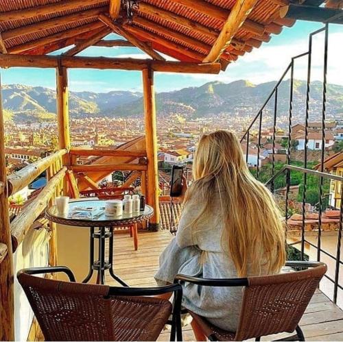 库斯科Cities of the World - Apartments Cusco的坐在阳台上桌子上的女人