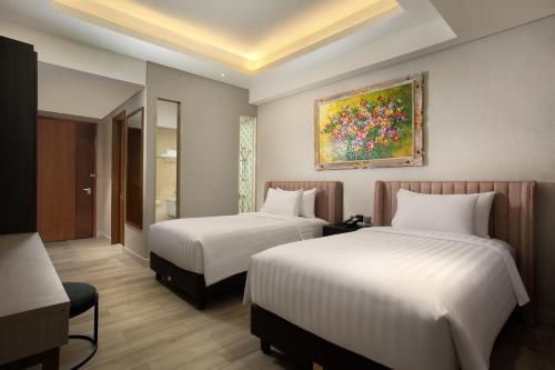 塞尔蓬Trembesi Hotel的酒店客房设有两张床,墙上挂有绘画作品