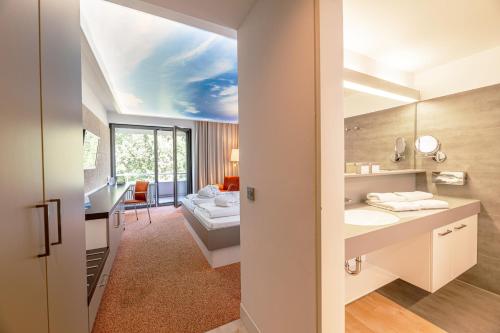 巴特布豪Thermenhotel Gesundheits-Bad Buchau的一间带水槽的浴室和一张位于客房内的床