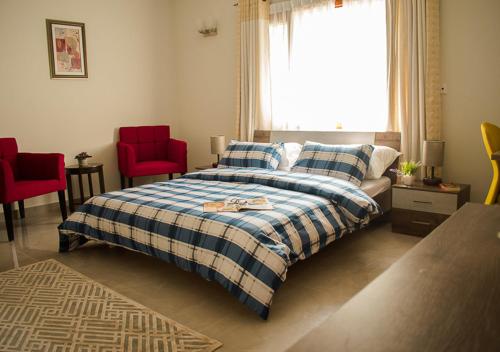 卡拉奇Hype Holiday Homes的一间卧室配有一张床和两张红色椅子