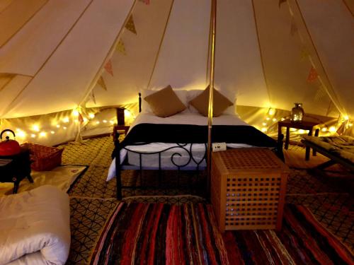滨海索尔特本Luxury 5m bell tent with log burner near Whitby的一个带床的卧室,位于带灯的帐篷内
