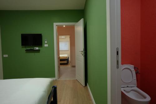 埃拉特RAKEFET - Traveler's House - EILAT的一间设有绿色墙壁、一张床和卫生间的客房