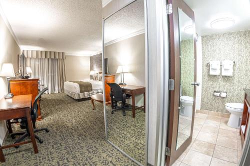 盐湖城Salt Lake Plaza Hotel SureStay Collection by Best Western的酒店客房设有带一张床和书桌的浴室。