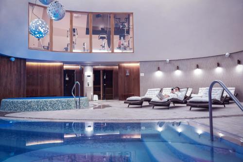 阿尼克什奇艾阿尼克什奇艾-维尔纽斯SPA酒店的坐在游泳池旁沙发上的女人