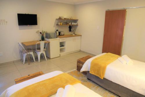 布隆方丹Nini's guest units的一间设有两张床、一间厨房和一张桌子的房间