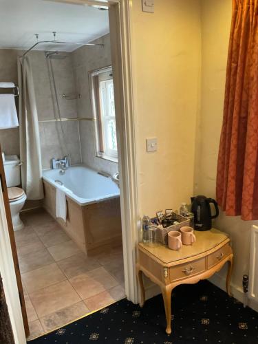 Bramley祖莉法玛宾馆的带浴缸的浴室以及带桌子和四柱床的桌子。