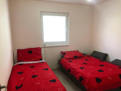 Szalócubytovanie u MITIho的一间卧室设有两张带红色床单的床和窗户。