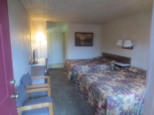 Grangeville城里人汽车旅馆的酒店客房带两张床和一张桌子以及椅子。