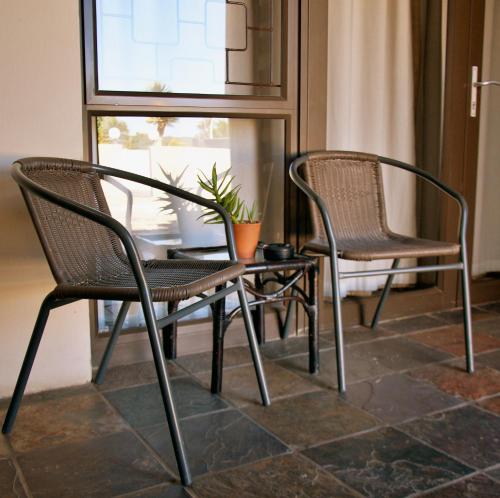 UitenhageMi Casa Guest House的两把椅子和一张桌子,上面有植物