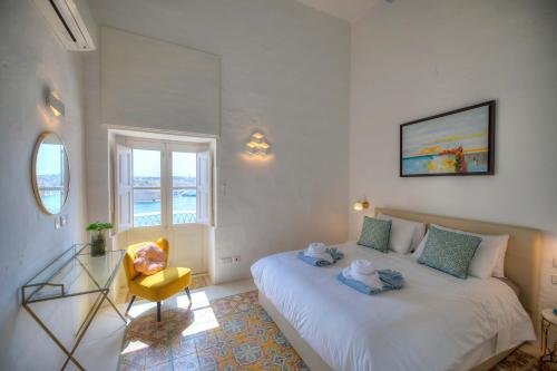 瓦莱塔Spacious maisonette with spectacular views IBRI1-1的卧室配有一张白色大床和一张黄色椅子