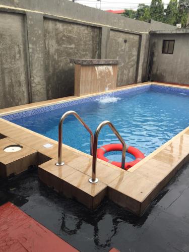 拉各斯Alluring View Hotel - Allen Avenue的一个带木甲板的游泳池和一个带喷泉的游泳池