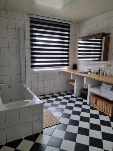 SwalmenVakantiewoning Schouwenberg的带浴缸的浴室和 ⁇ 格地板