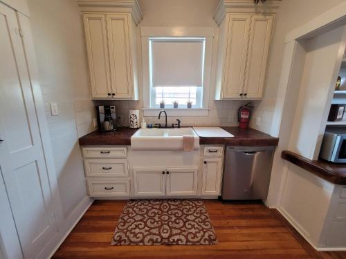 阿尔派恩Holland House - Historic and Sophisticated的厨房配有白色橱柜、水槽和地毯。