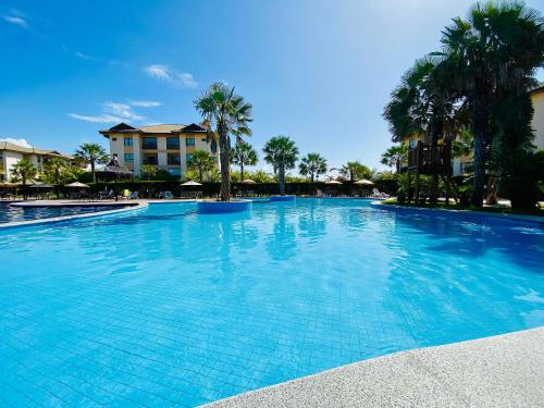 考卡亚Resort VG SUN por Be My Guest!的一座种植了棕榈树和建筑的大型蓝色游泳池