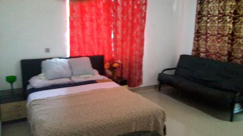 阿克拉Hayben serviced apartments的一间卧室配有床、沙发和红色窗帘