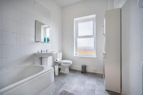 利Modern spacious 2 bedroom house in Leigh Self Service的白色的浴室设有浴缸、卫生间和水槽。