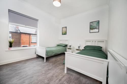 利Modern spacious 2 bedroom house in Leigh Self Service的一间卧室设有两张床和窗户。