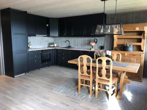 贝特斯托尔Beitotind sentralt på Beitostølen的厨房配有黑色橱柜和木桌及椅子
