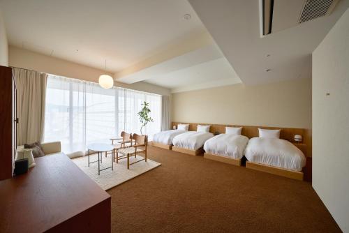 松山Hotel Lepo Chahal的一间卧室设有四张床和一张桌子及椅子