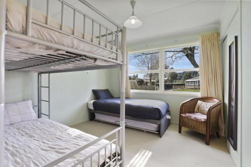 图朗伊Pukeko Lodge - Tūrangi Holiday Home的一间卧室配有两张双层床和椅子