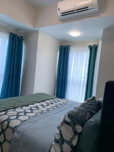 马尼拉Le Maisse Executive Studio 1BR opp Okada的一间卧室配有一张带蓝色窗帘的床和风扇