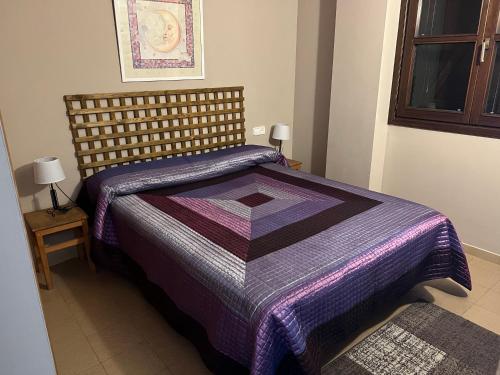 埃斯波特Apartamento a pie de pistas de Espot ZZ House的一间卧室配有一张带紫色棉被的床