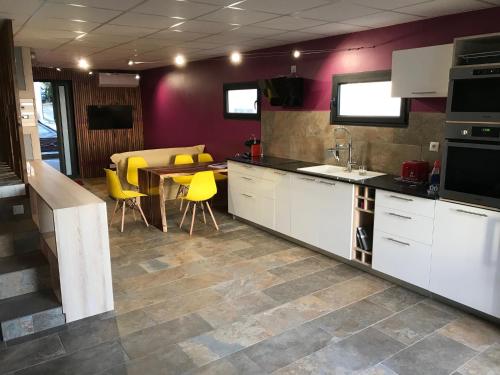珀蒂蒂勒loft meublé fonctionnel proche de grande anse的厨房配有白色橱柜、桌子和黄色椅子