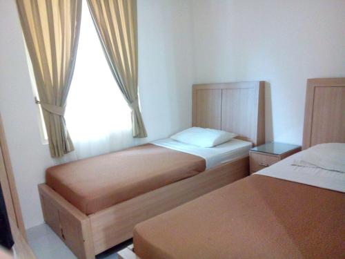 PadangThe Abidin Hotel Syari'ah的一间小卧室,配有两张床和窗户
